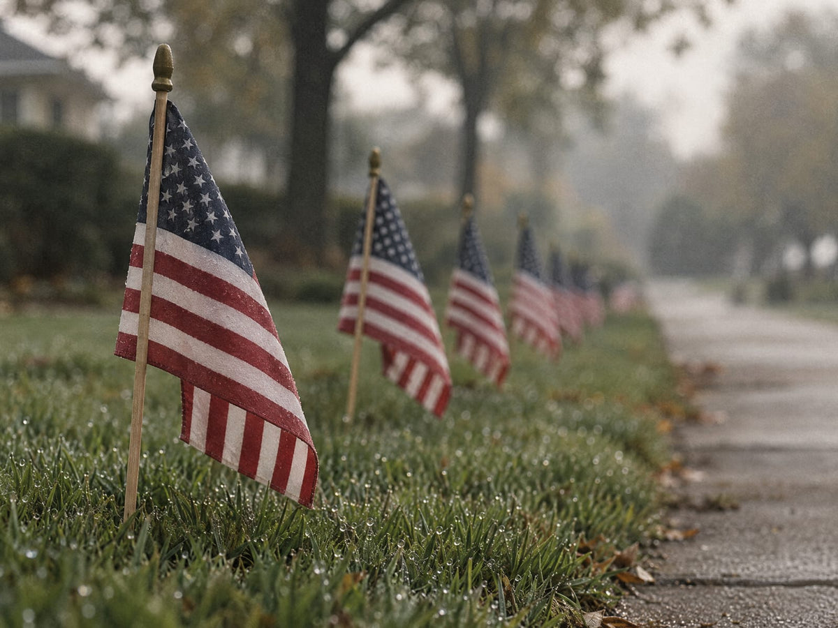 Row of small American flags planted along a lawn on a misty morning